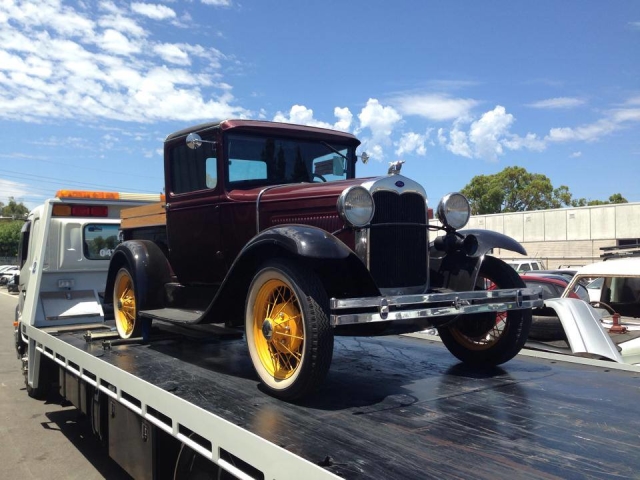 vintage car being transported with a tilt tray truck